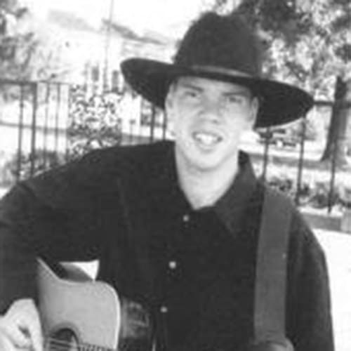 A man celebrating homecoming in 2000 with a black cowboy hat and guitar.